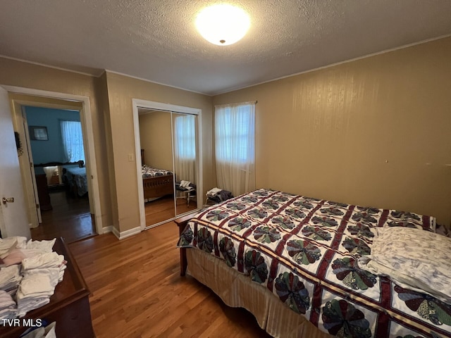 bedroom featuring hardwood / wood-style flooring, a textured ceiling, and a closet