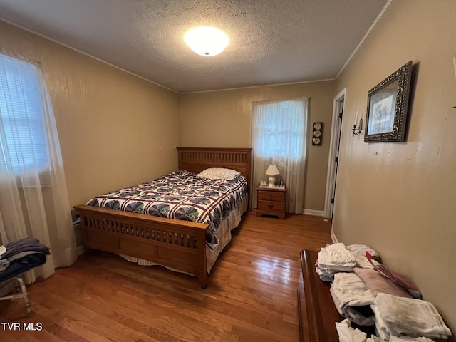 bedroom with hardwood / wood-style flooring, crown molding, and a textured ceiling