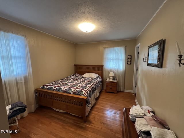 bedroom with ornamental molding, a textured ceiling, and light hardwood / wood-style flooring