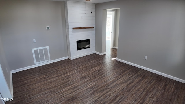 unfurnished living room featuring a large fireplace and dark hardwood / wood-style floors