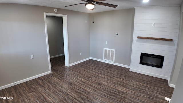 unfurnished living room featuring a textured ceiling, ceiling fan, dark hardwood / wood-style flooring, and a fireplace