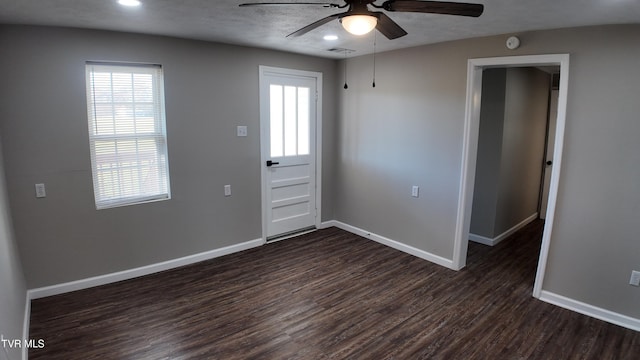 empty room featuring ceiling fan, dark wood-type flooring, and a textured ceiling