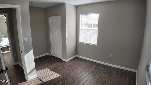 unfurnished bedroom featuring dark hardwood / wood-style flooring and a closet