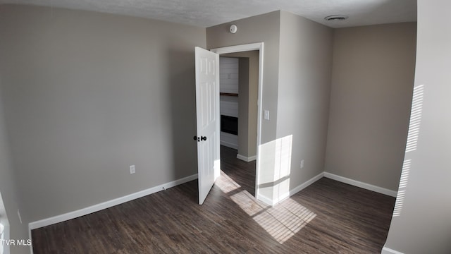 spare room with a textured ceiling and dark hardwood / wood-style floors