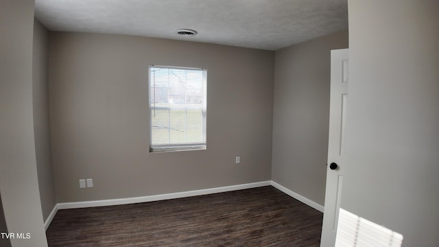 unfurnished room with a textured ceiling and dark wood-type flooring