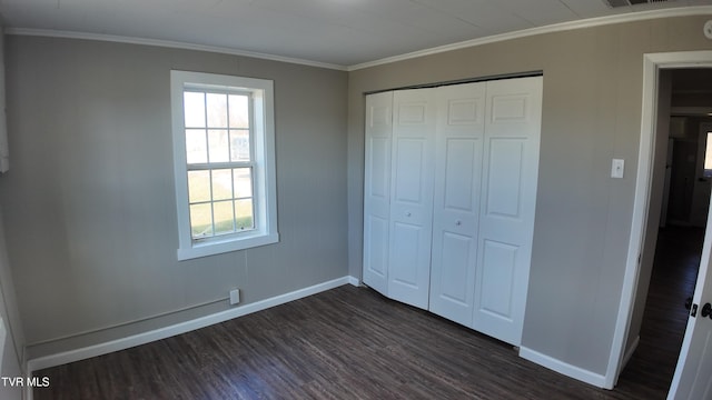 unfurnished bedroom with ornamental molding, dark wood-type flooring, and a closet