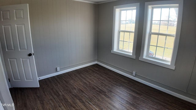 spare room with dark hardwood / wood-style floors, wood walls, and ornamental molding