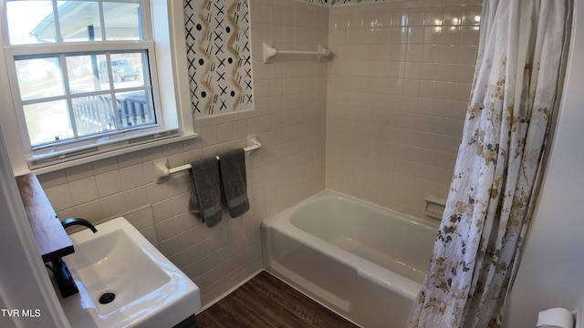 bathroom featuring sink, wood-type flooring, tile walls, and shower / tub combo with curtain