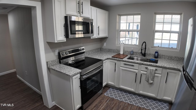 kitchen with sink, stainless steel appliances, light stone counters, dark hardwood / wood-style flooring, and white cabinets