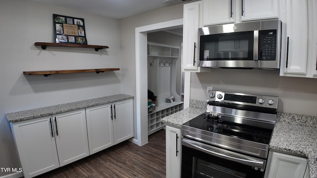 kitchen with white cabinets, dark hardwood / wood-style floors, light stone counters, and appliances with stainless steel finishes