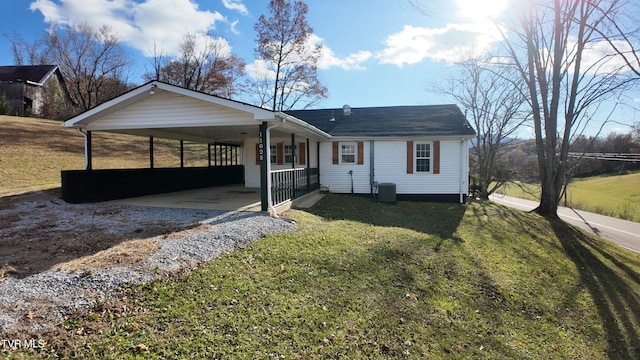 view of front of property featuring a carport, covered porch, central air condition unit, and a front yard