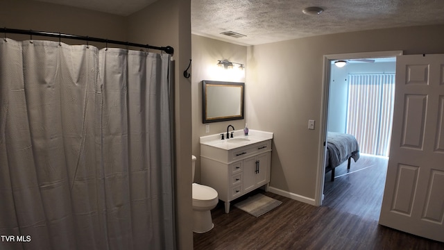 bathroom featuring hardwood / wood-style floors, vanity, ceiling fan, toilet, and a textured ceiling