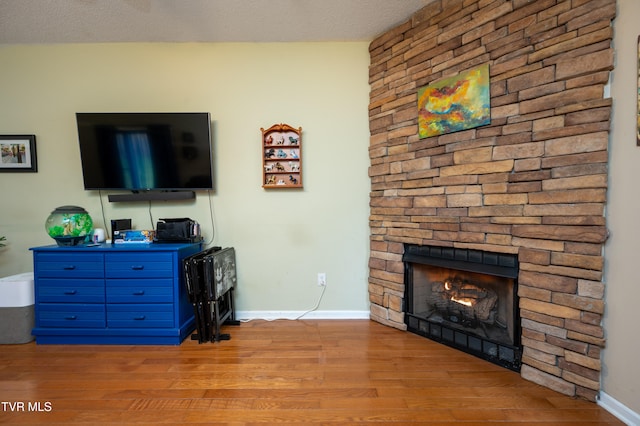 living room with a fireplace, a textured ceiling, and light wood-type flooring