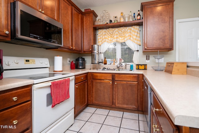 kitchen with sink, light tile patterned floors, stainless steel appliances, and a textured ceiling