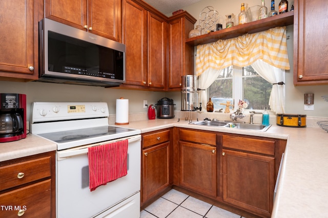 kitchen with white range with electric cooktop, sink, and light tile patterned floors