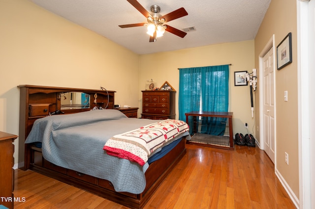 bedroom with wood-type flooring, a textured ceiling, and ceiling fan