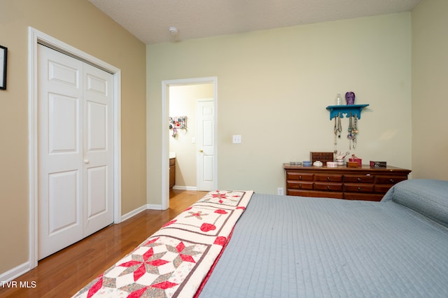 bedroom with a closet, wood-type flooring, and a textured ceiling