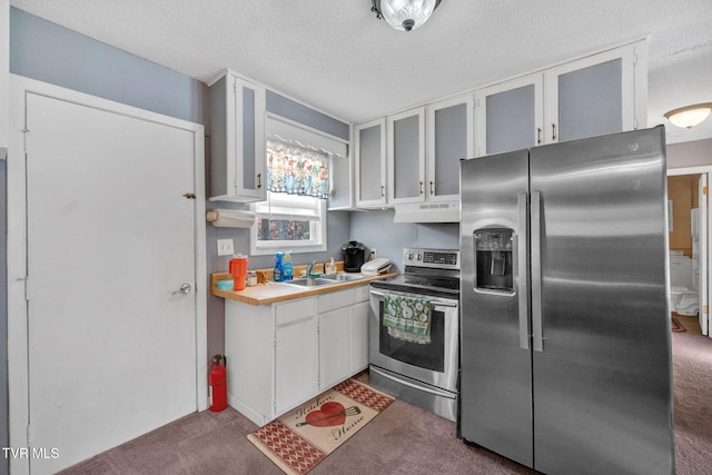 kitchen featuring a textured ceiling, stainless steel appliances, sink, white cabinets, and carpet floors