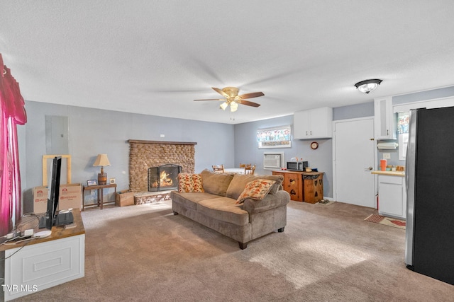 living room featuring carpet flooring, ceiling fan, a textured ceiling, and a brick fireplace