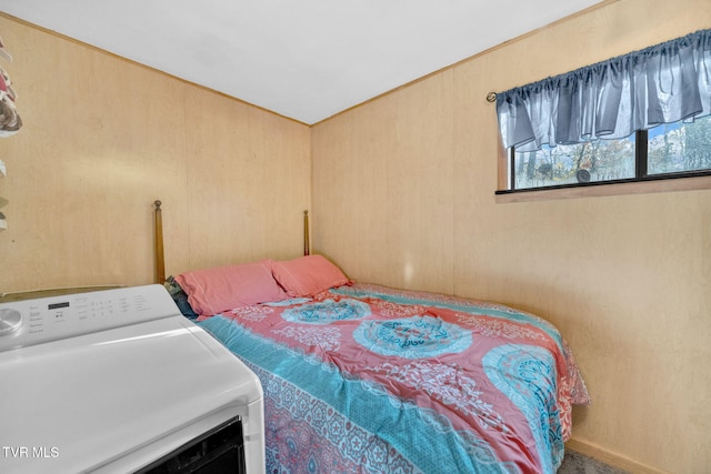 bedroom featuring washer / clothes dryer and wood walls