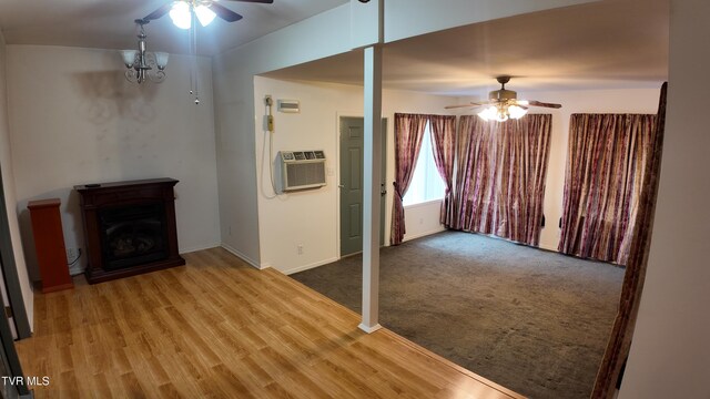 unfurnished living room featuring ceiling fan with notable chandelier, an AC wall unit, and hardwood / wood-style floors