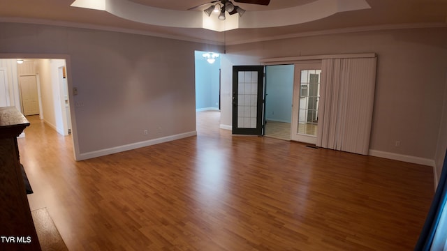 spare room with ornamental molding, hardwood / wood-style flooring, ceiling fan, and a raised ceiling