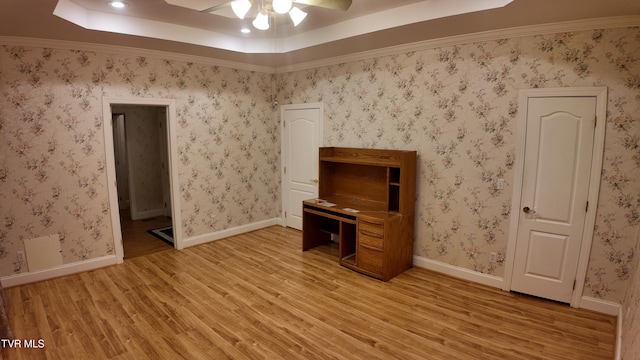 interior space with light hardwood / wood-style floors, ceiling fan, and a tray ceiling