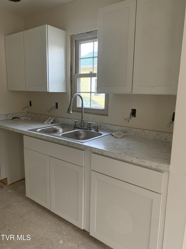 kitchen with white cabinets, light stone counters, and sink