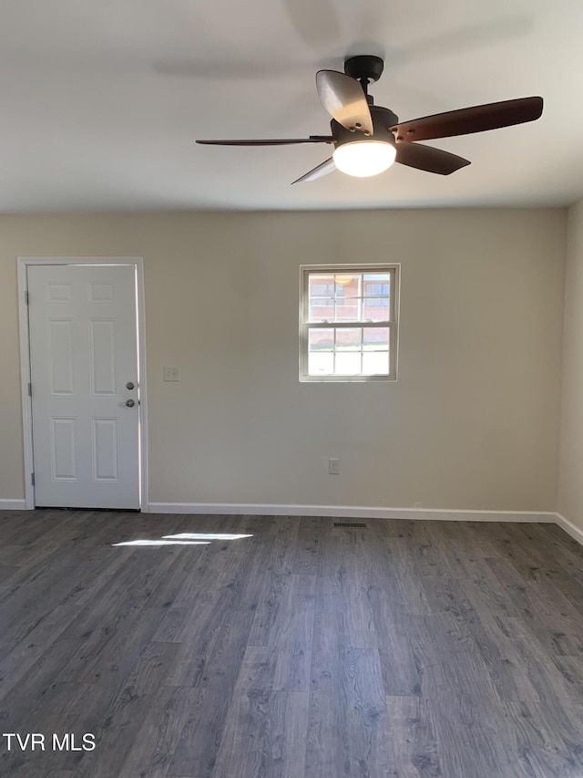 unfurnished room with visible vents, baseboards, and dark wood-type flooring