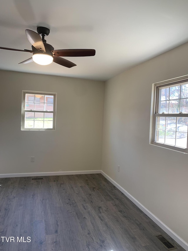 empty room with visible vents, baseboards, ceiling fan, and dark wood-style flooring