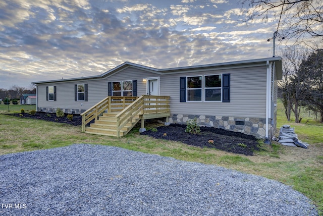 manufactured / mobile home featuring a wooden deck and a front yard