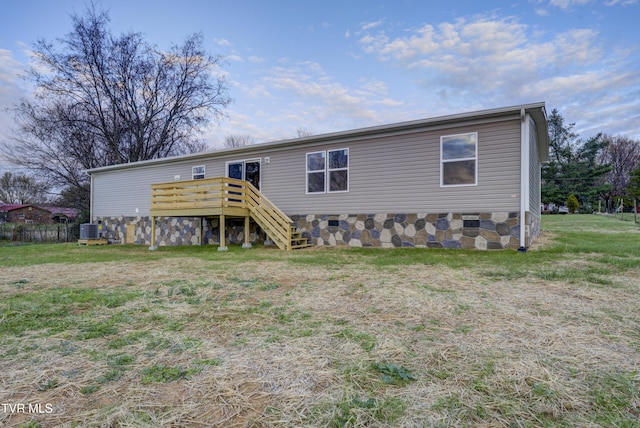 view of front of home with a front yard, central AC, and a wooden deck