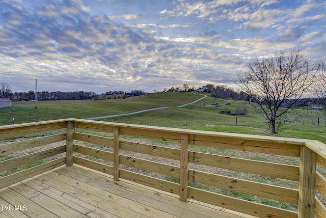 wooden terrace featuring a rural view and a yard