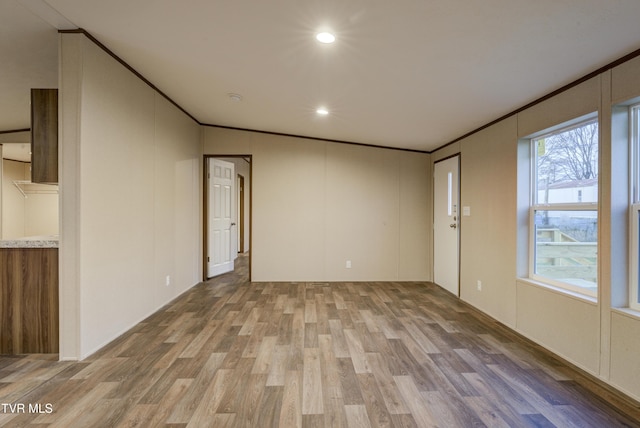 empty room featuring hardwood / wood-style floors, vaulted ceiling, and ornamental molding