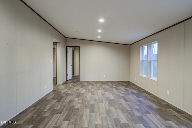 unfurnished room with hardwood / wood-style flooring, lofted ceiling, and crown molding