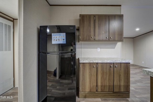 kitchen featuring black fridge, light hardwood / wood-style floors, and ornamental molding