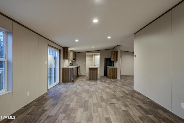 unfurnished living room featuring wood-type flooring, vaulted ceiling, and crown molding