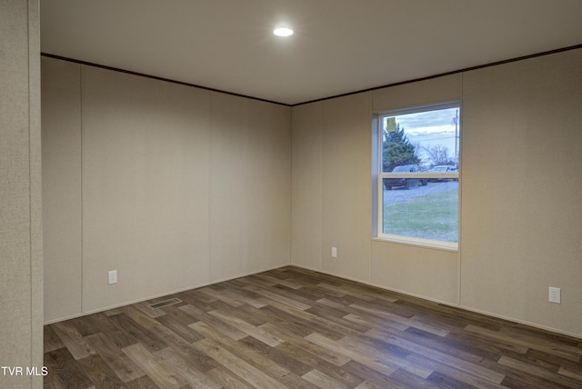 spare room featuring wood-type flooring and crown molding