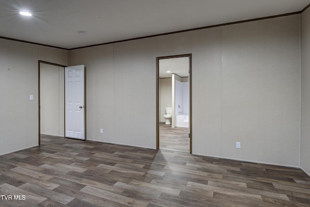 unfurnished bedroom with hardwood / wood-style flooring, ensuite bathroom, and ornamental molding