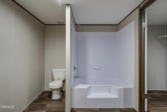 bathroom with hardwood / wood-style flooring, toilet, and bathtub / shower combination