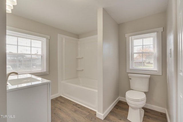 full bathroom with washtub / shower combination, hardwood / wood-style floors, vanity, and toilet