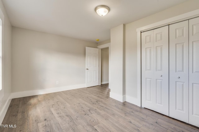 unfurnished bedroom with light wood-type flooring and a closet