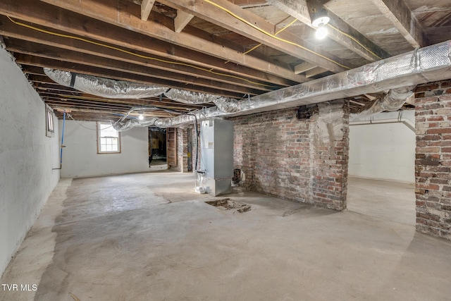 basement featuring brick wall and heating unit