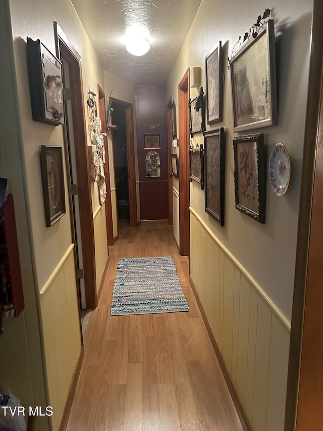 corridor featuring light hardwood / wood-style floors and a textured ceiling