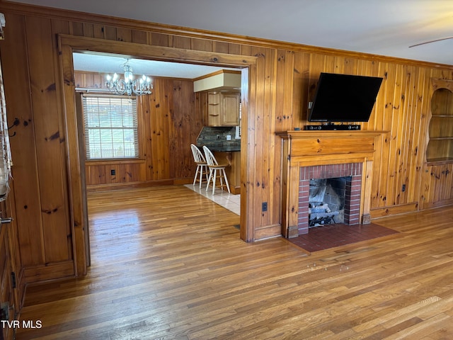 unfurnished living room featuring wood-type flooring, an inviting chandelier, and wood walls