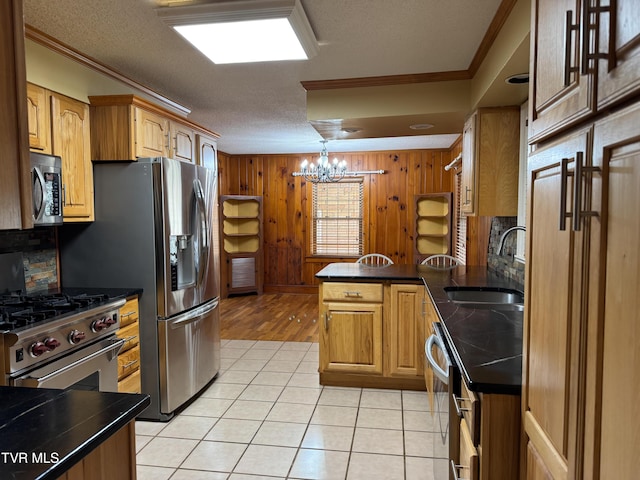 kitchen featuring decorative backsplash, appliances with stainless steel finishes, sink, a chandelier, and light tile patterned flooring