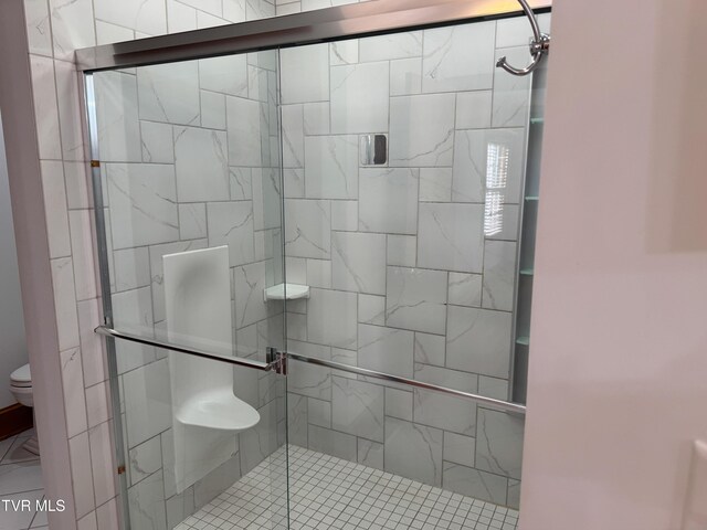 bathroom with a shower with door and toilet