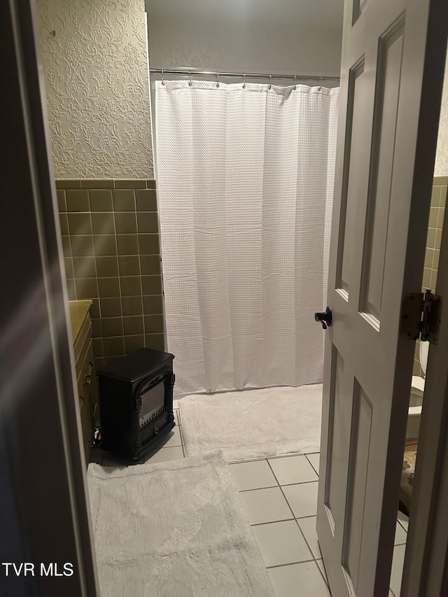 bathroom with tile patterned flooring, tile walls, and a wood stove