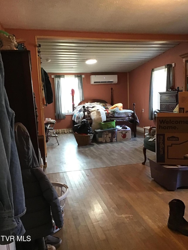 bedroom with a wall mounted AC and light hardwood / wood-style flooring