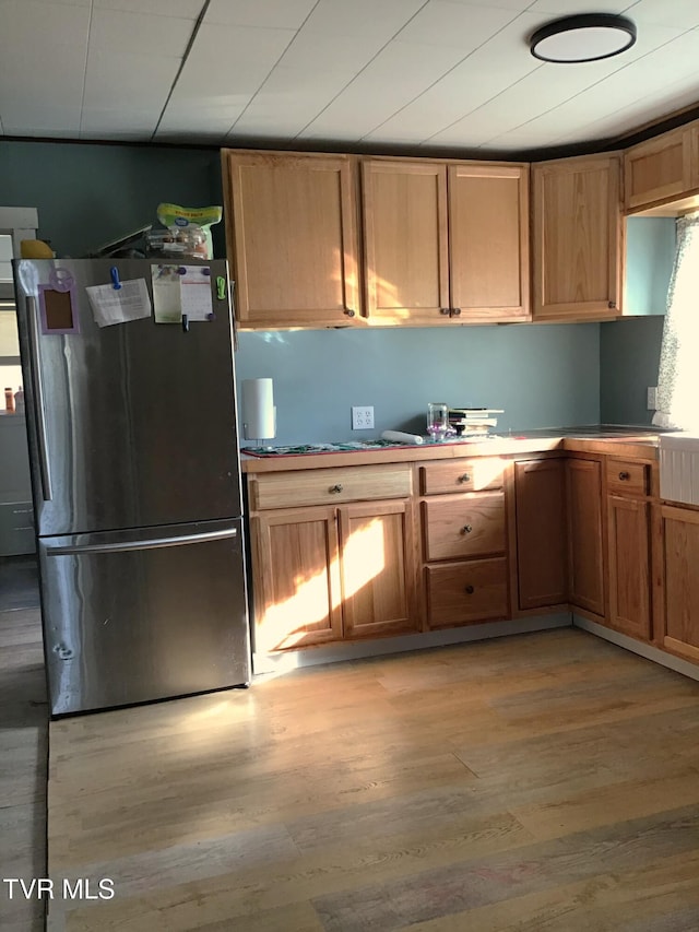 kitchen with light wood-type flooring and stainless steel refrigerator